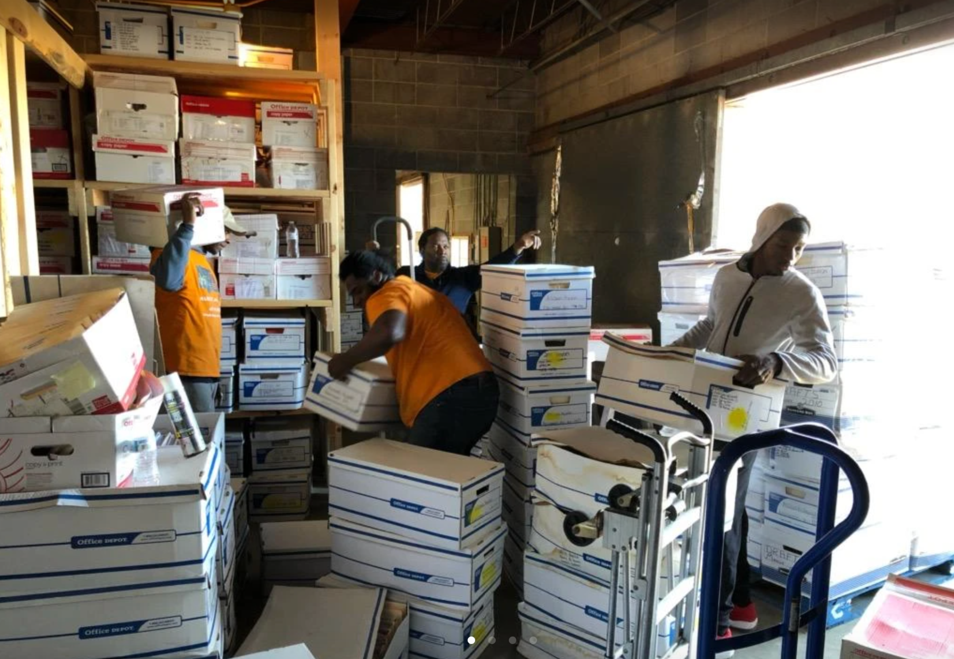 A group of people are moving boxes in a warehouse.
