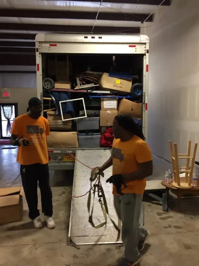 Two men are loading a moving truck with boxes and furniture.
