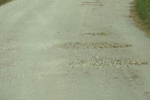 Gravel road with three weathered sections across the surface.