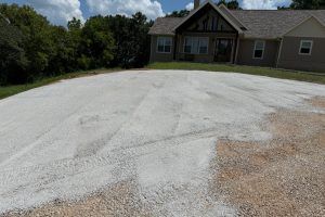 A gravel driveway in front of a house. The sky is blue.