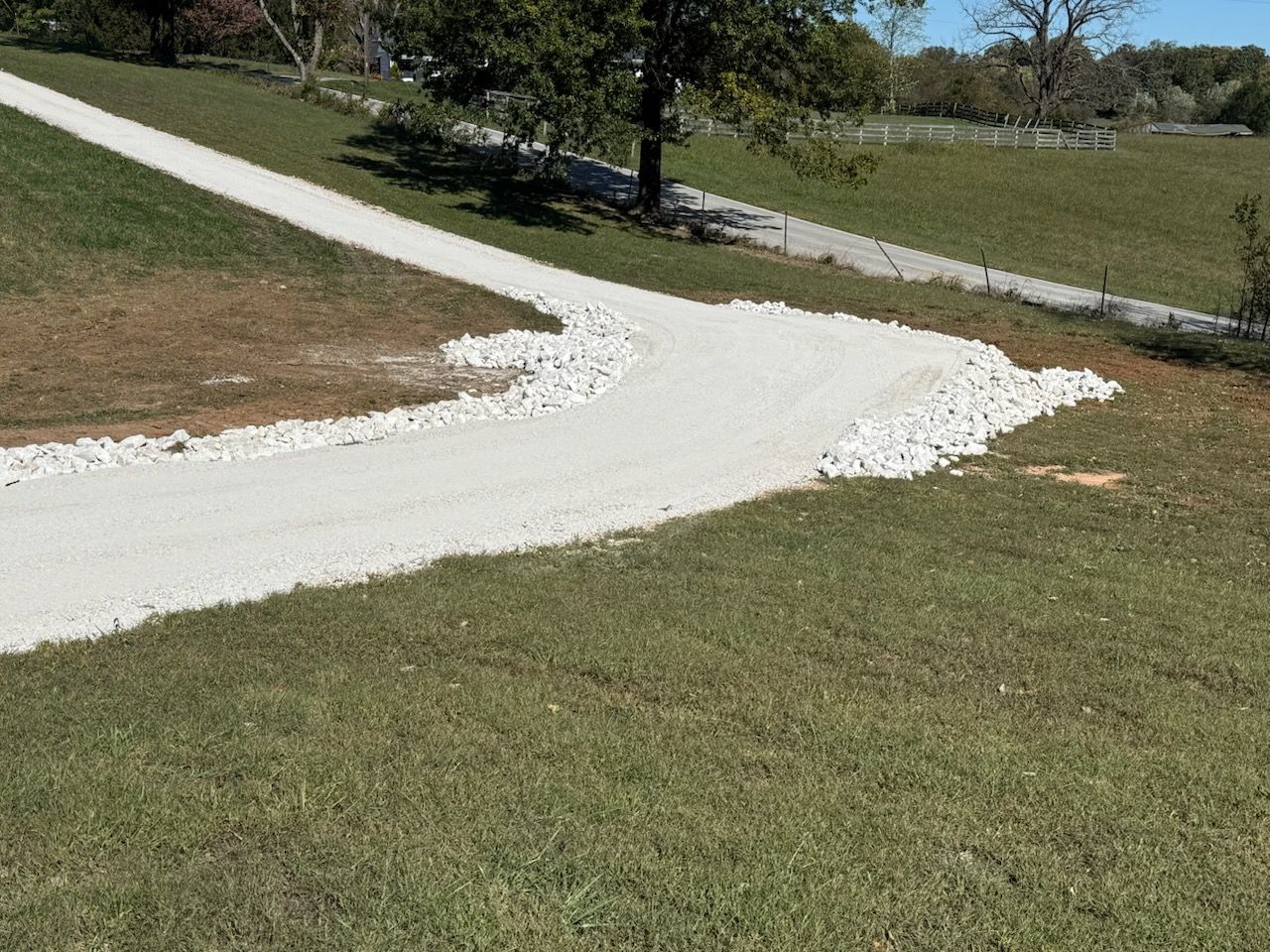 White gravel driveway curves through grassy terrain.