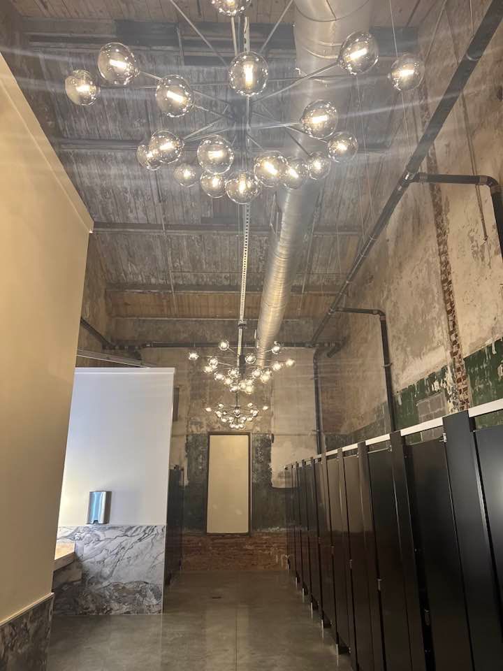 Industrial interior with exposed brick, hanging globe lights, and dark locker-style cabinets.