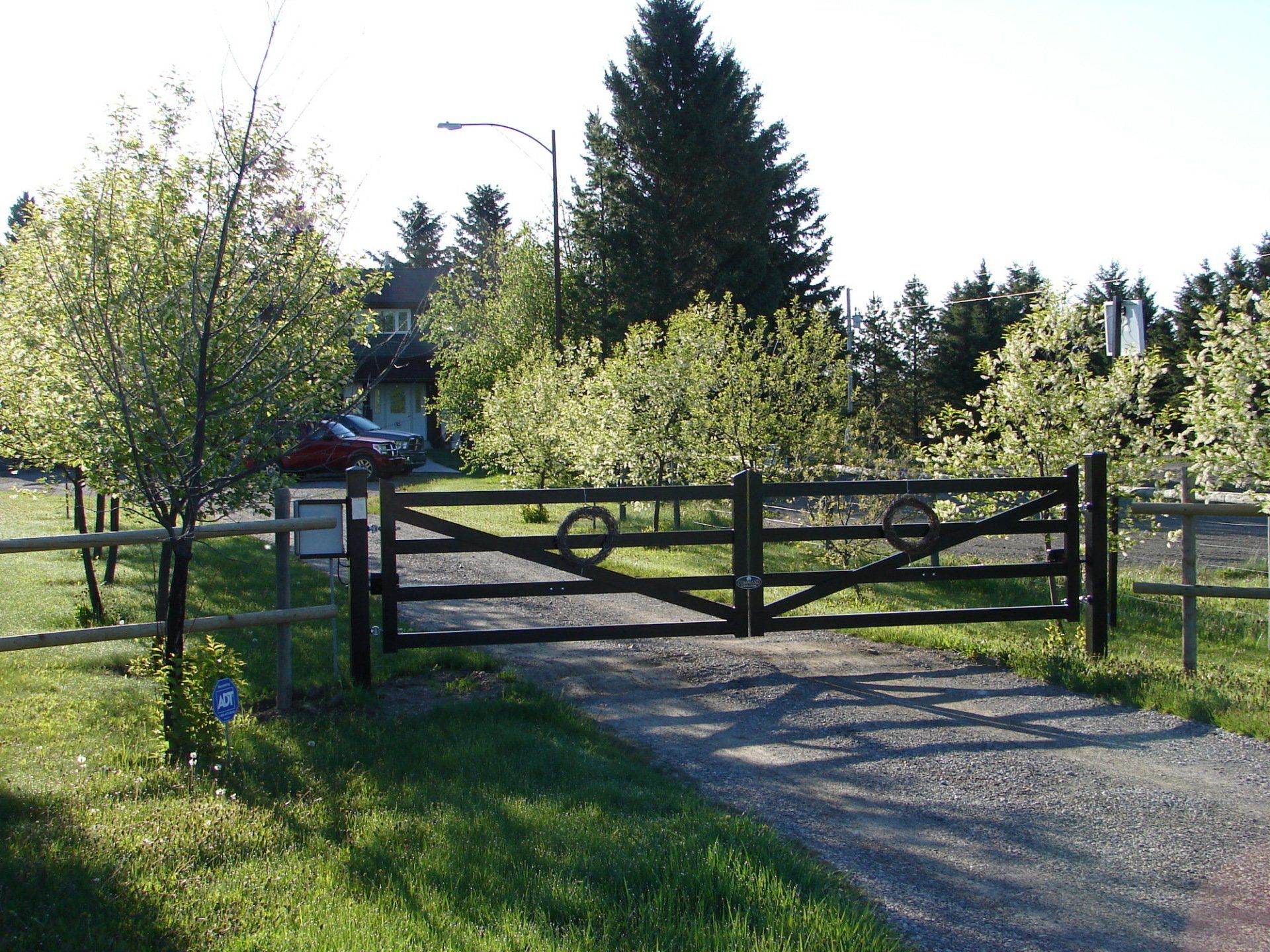 A red car is parked behind a wooden gate