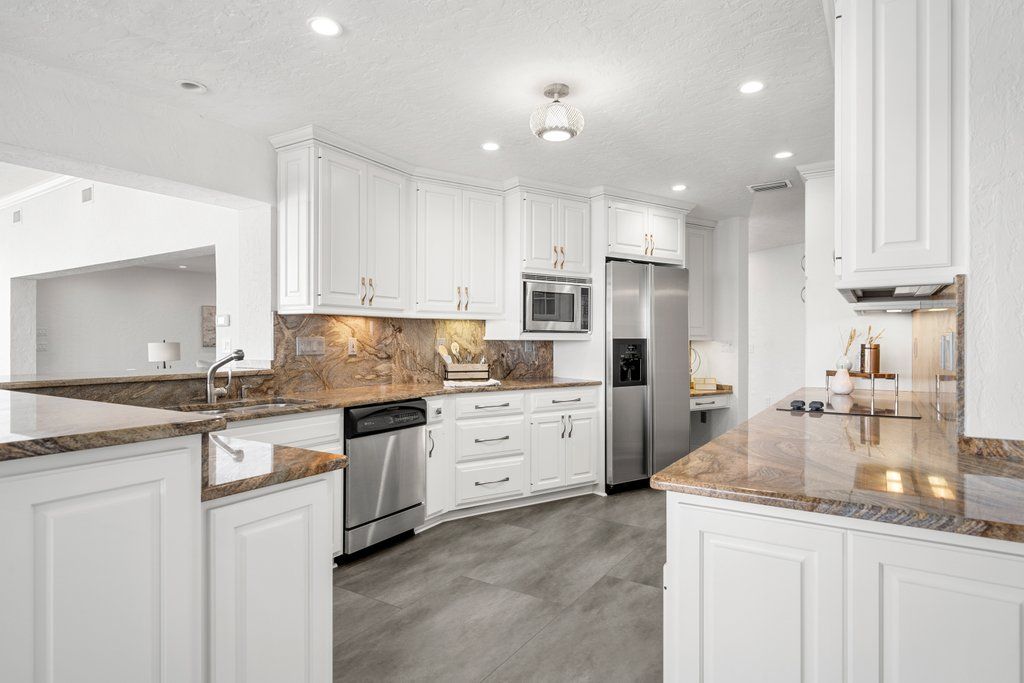 Spacious kitchen with wooden cabinets, an island, and stainless steel refrigerator on tile floor. Spacious kitchen with wooden cabinets, an island, and stainless steel refrigerator on tile floor.