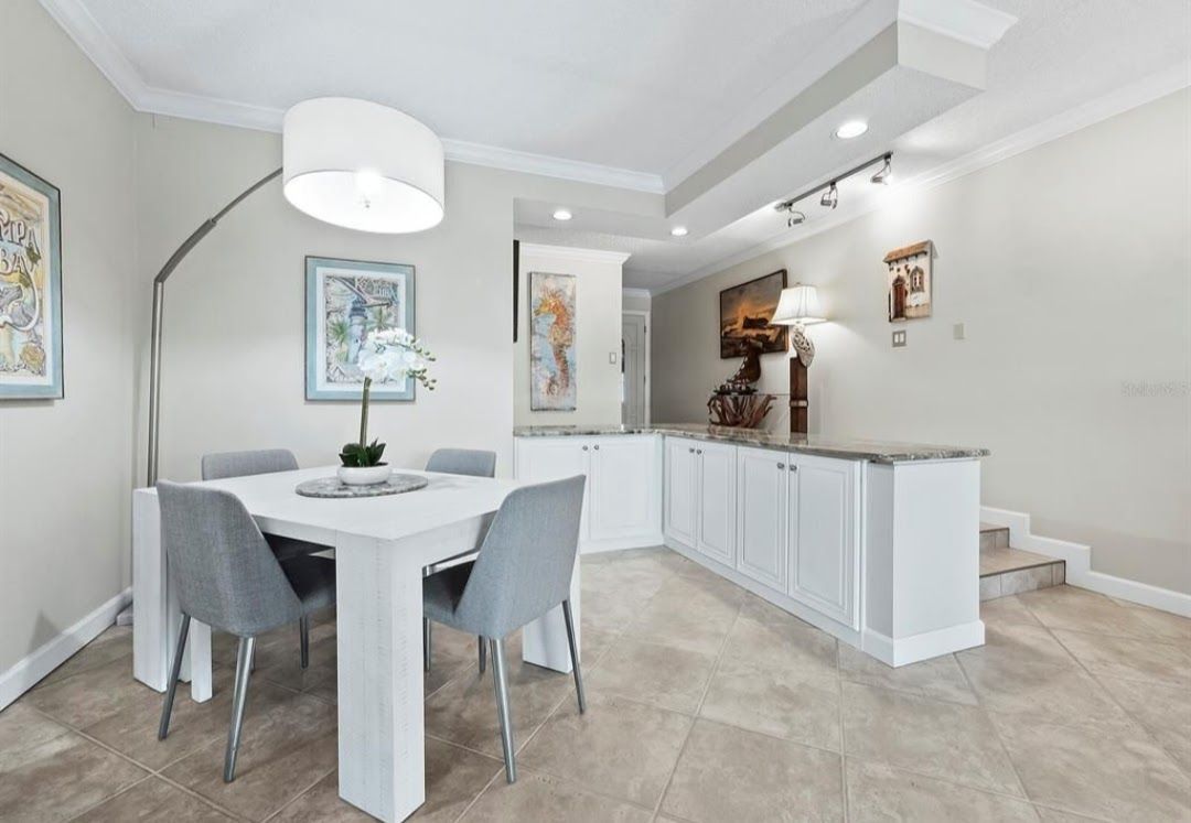 Dining room with white table, gray chairs, and overhead lighting. Dining room with white table, gray chairs, and overhead lighting.
