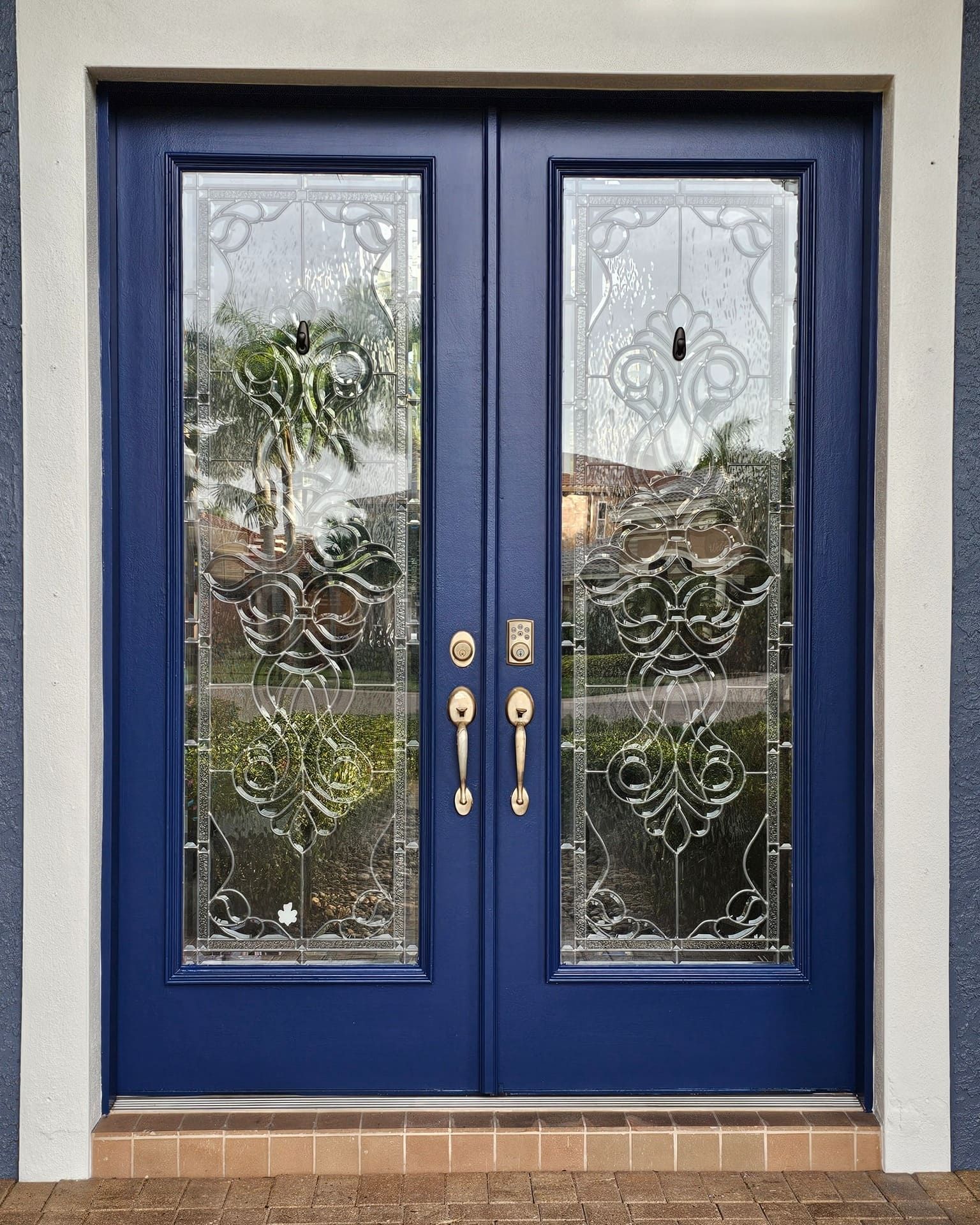 Blue double doors with decorative glass panes and brass hardware.