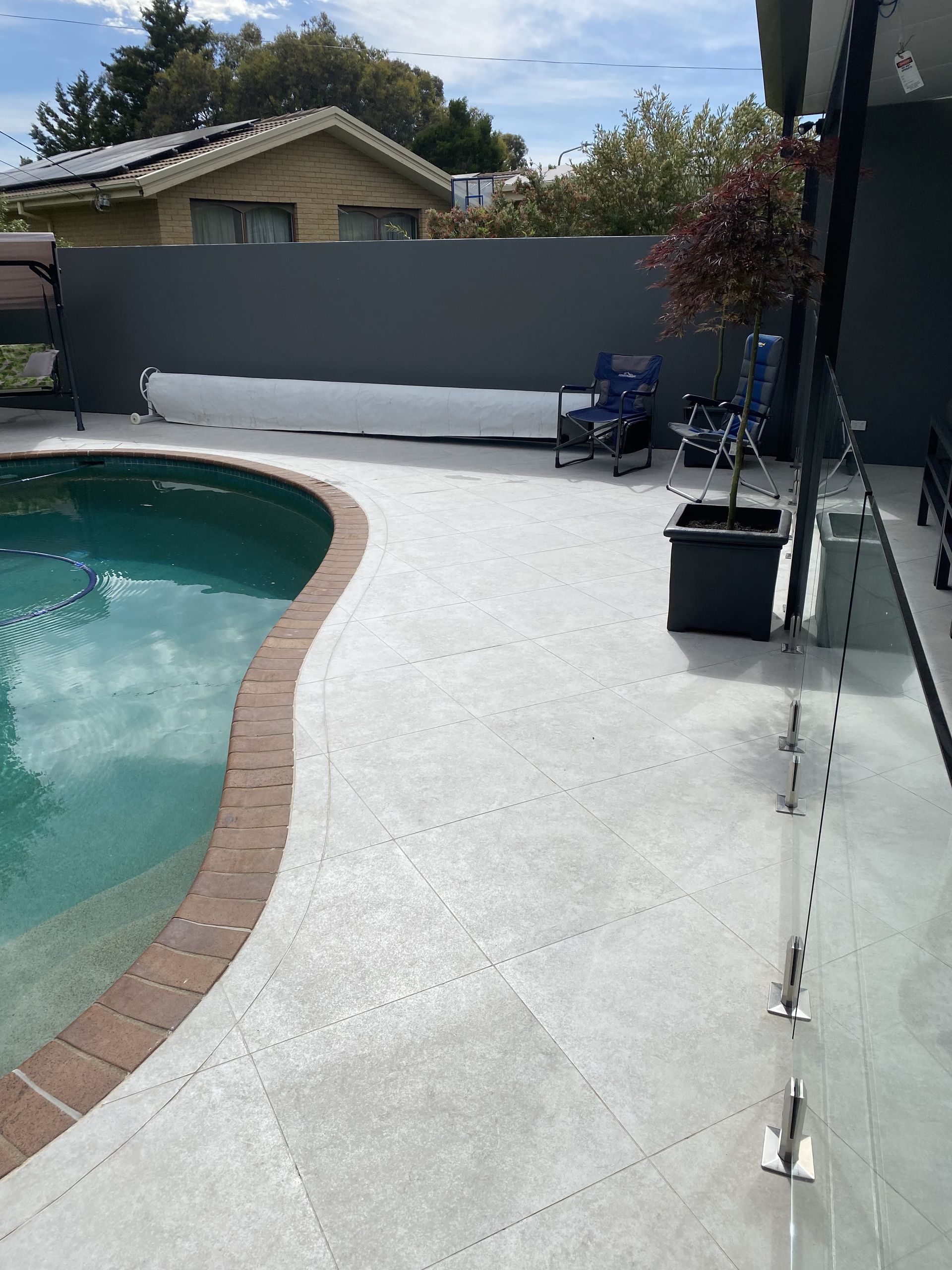 Poolside Concrete Patio With a Pool — Rectified Edge Tiling & Bathroom Renovations in Queanbeyan, NSW