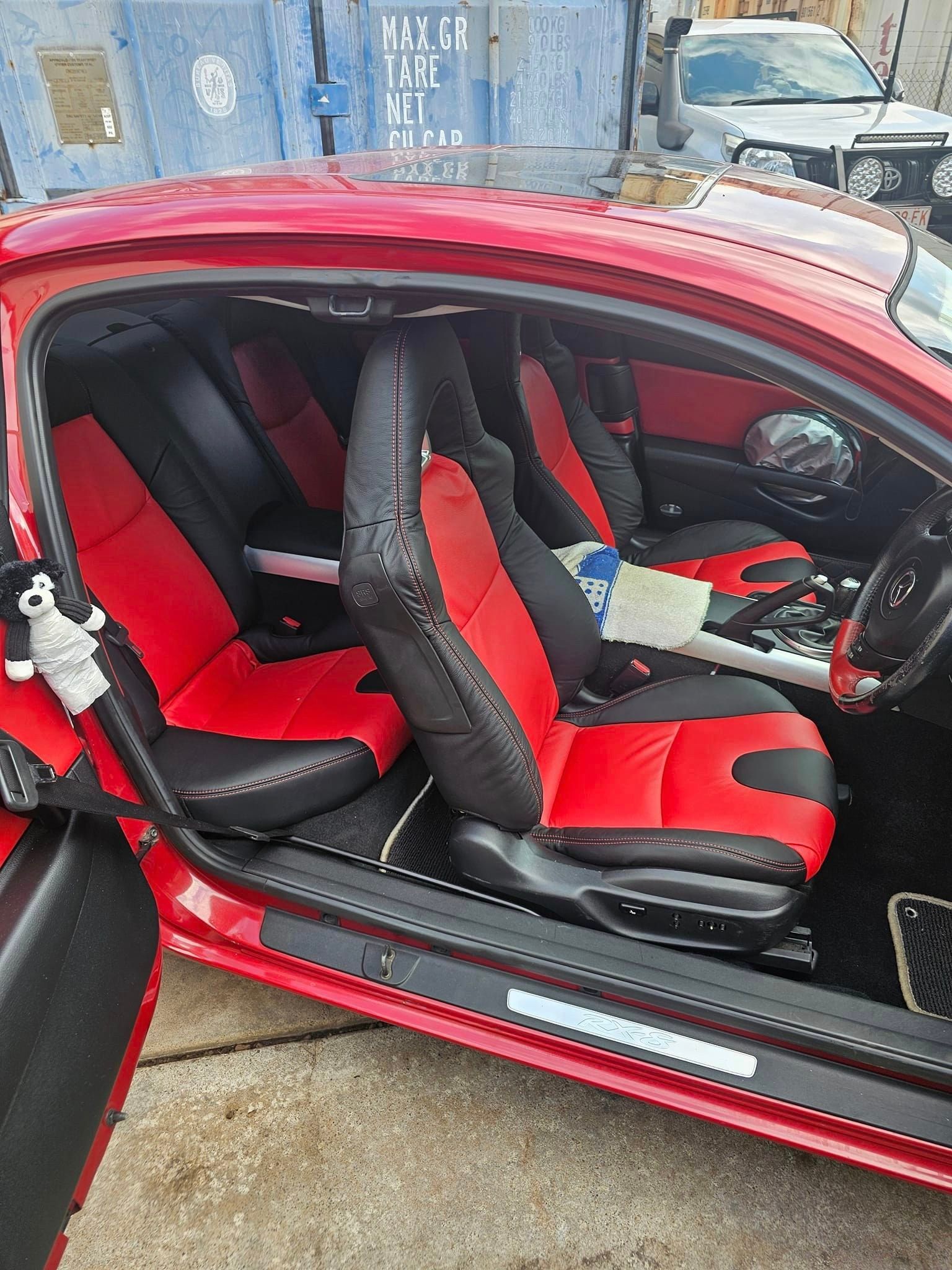 A Red Car Is Parked In A Parking Lot In Front Of A Building — All Car Upholstery In Pinelands, NT