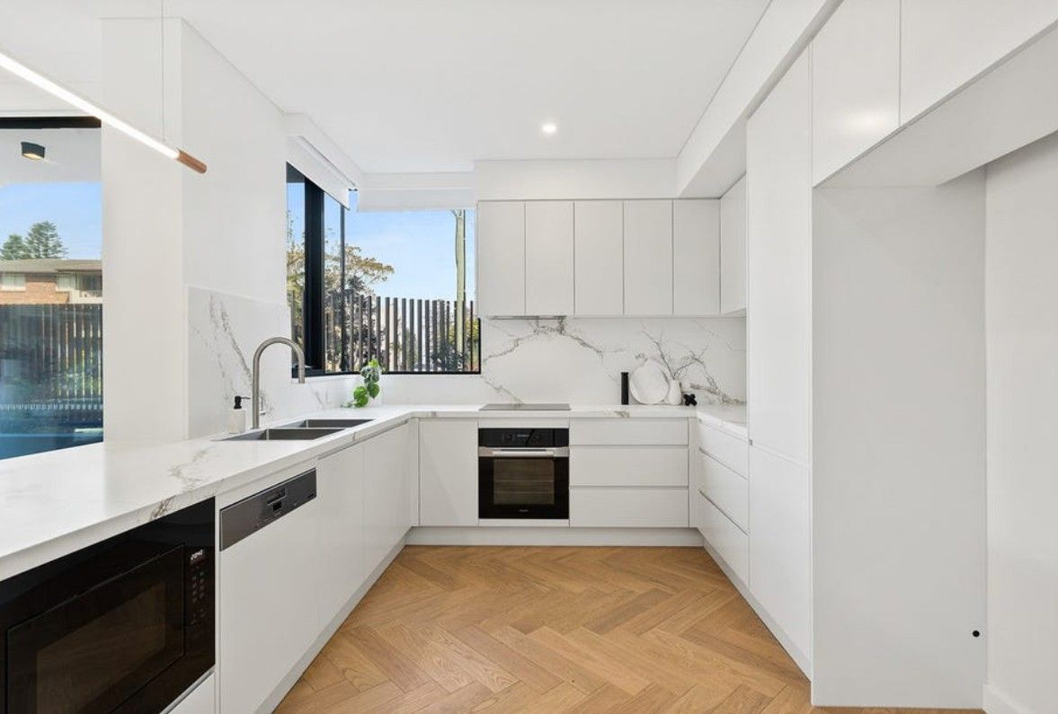 A kitchen with white cupboards, a sink and an oven — Commercial Painting Group in Shellharbour, NSW