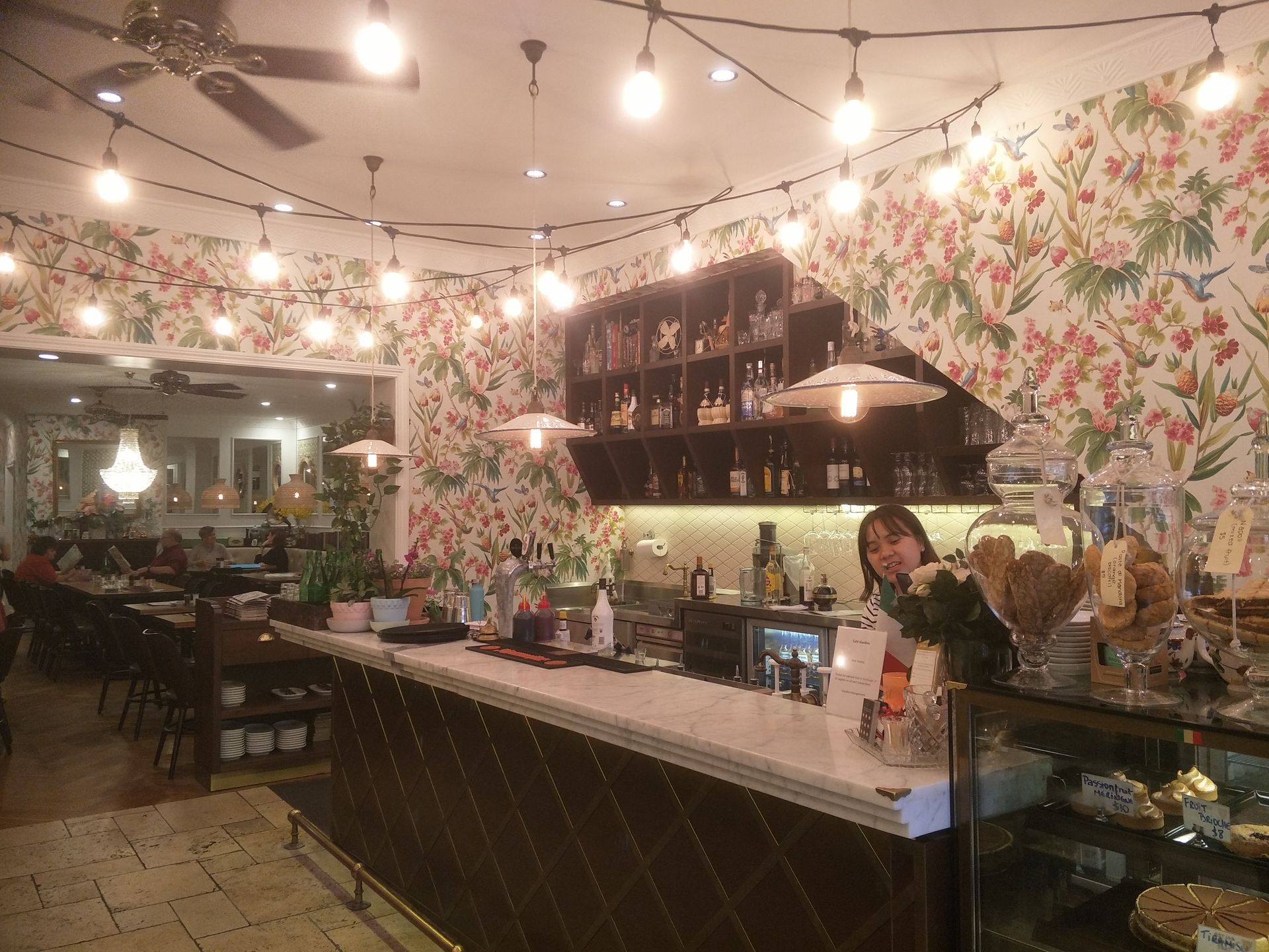 A bar with downlights, colourful wallpaper and a woman standing behind the bench — Commercial Painting Group in Central West, NSW