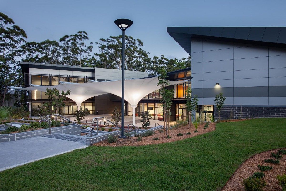 An outdoor area with white shade sails and a large building — Commercial Painting Group in Kiama, NSW