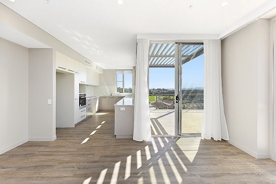 An Empty Room With a Sliding Glass Door Leading to a Kitchen — Commercial Painting Group in Shellharbour, NSW