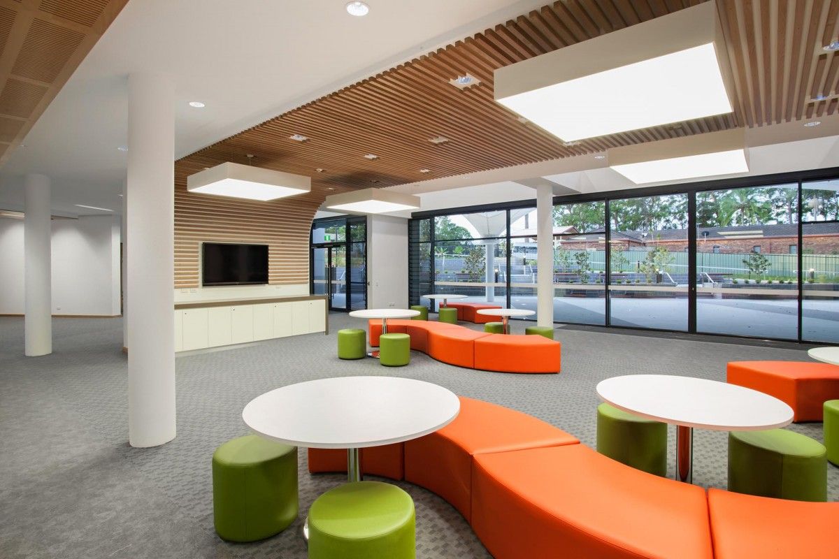 A large room with white tables and orange and green chairs — Commercial Painting Group in Canberra, ACT