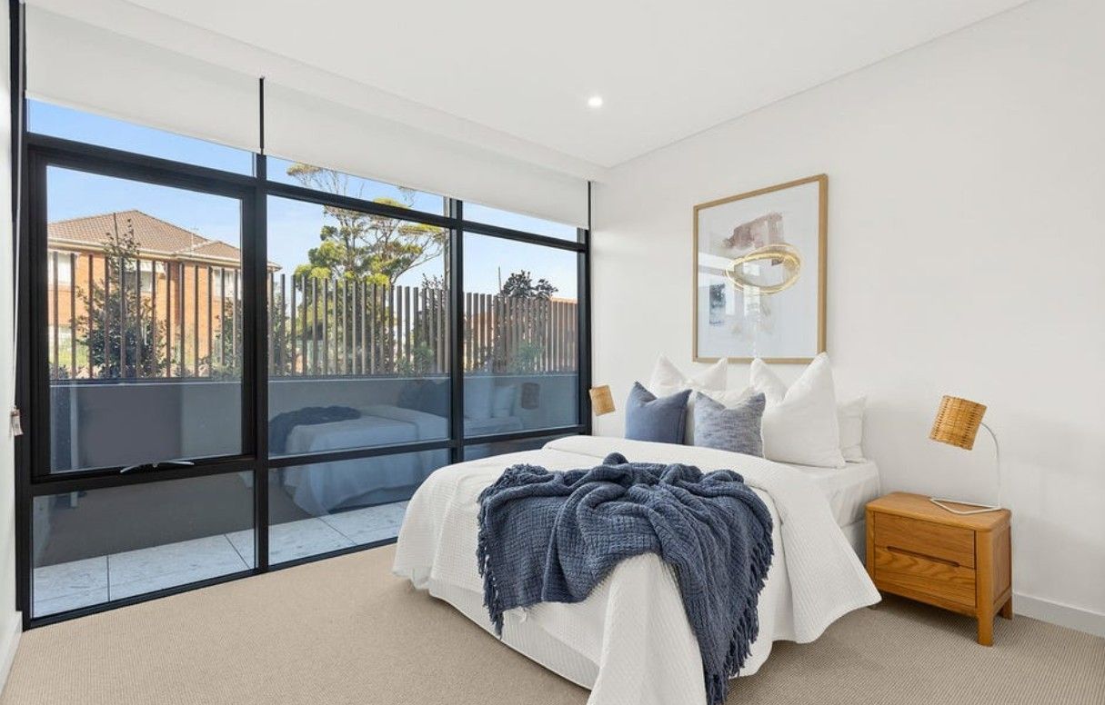 A bedroom with large windows and a bed with a blue blanket — Commercial Painting Group in Kembla Grange, NSW