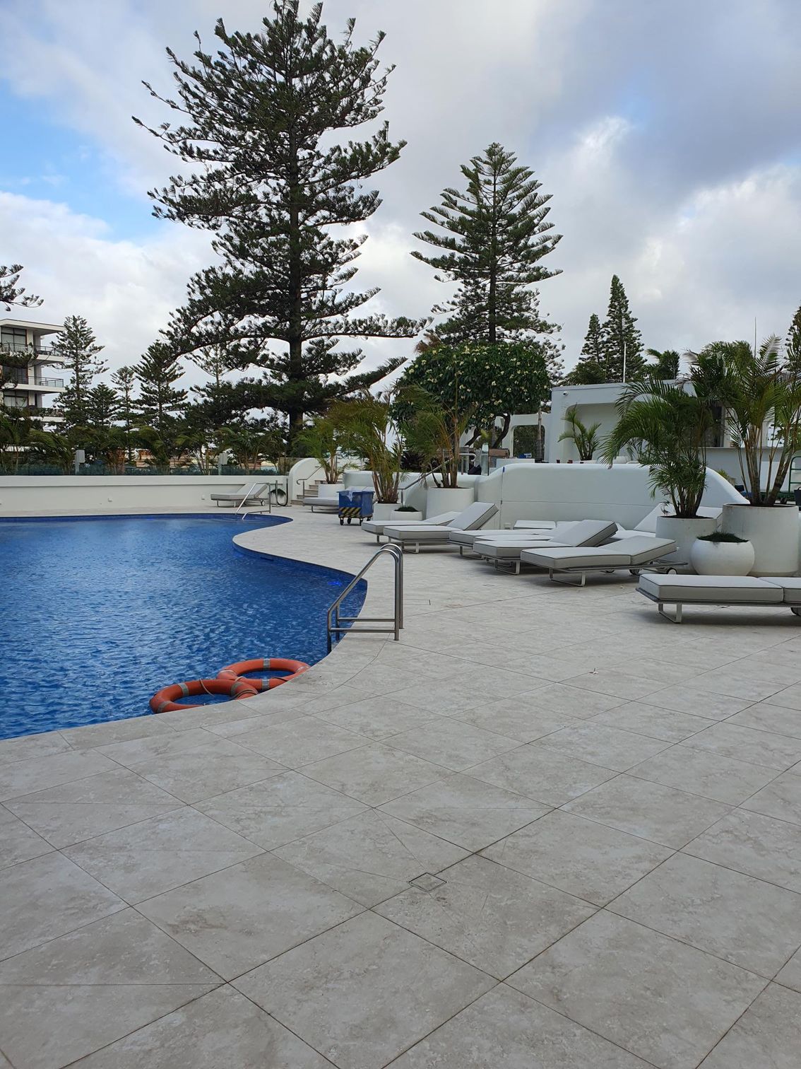 A pool area with life rings floating in the pool and deck chairs — Commercial Painting Group in Kembla Grange, NSW