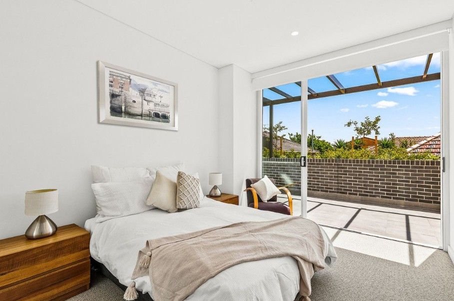A bedroom with white walls and a bed and open door looking outside — Commercial Painting Group in Kembla Grange, NSW