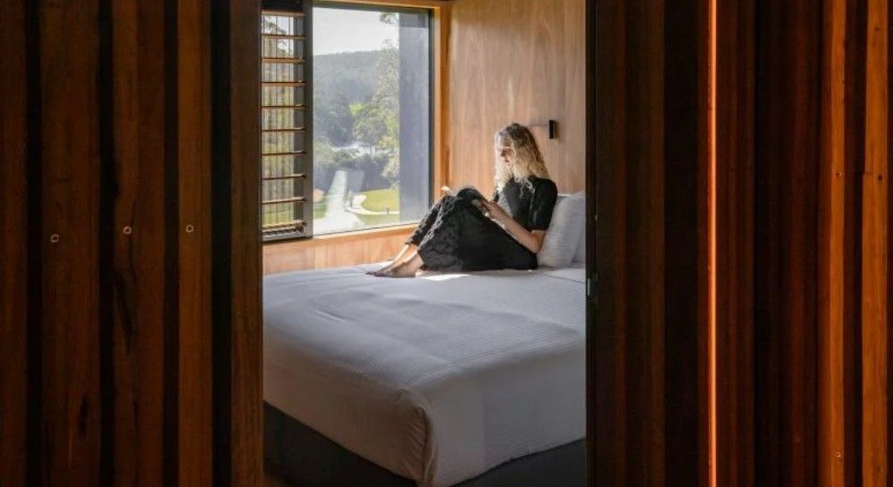 A woman is sitting on a bed reading — Commercial Painting Group in Kembla Grange, NSW