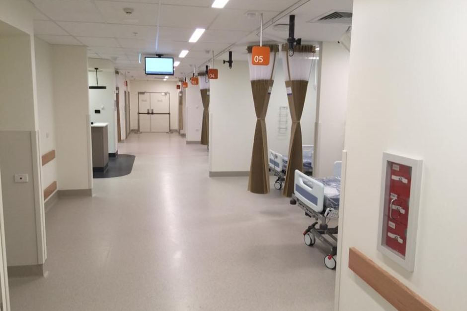 A hospital corridor with hospital beds and brown curtains — Commercial Painting Group in Kembla Grange, NSW
