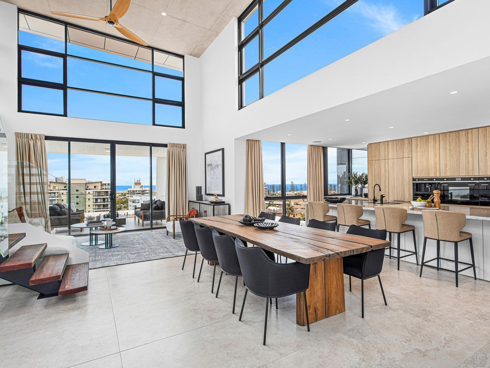 A dining room with a big wooden table and eight black chairs — Commercial Painting Group in Kembla Grange, NSW
