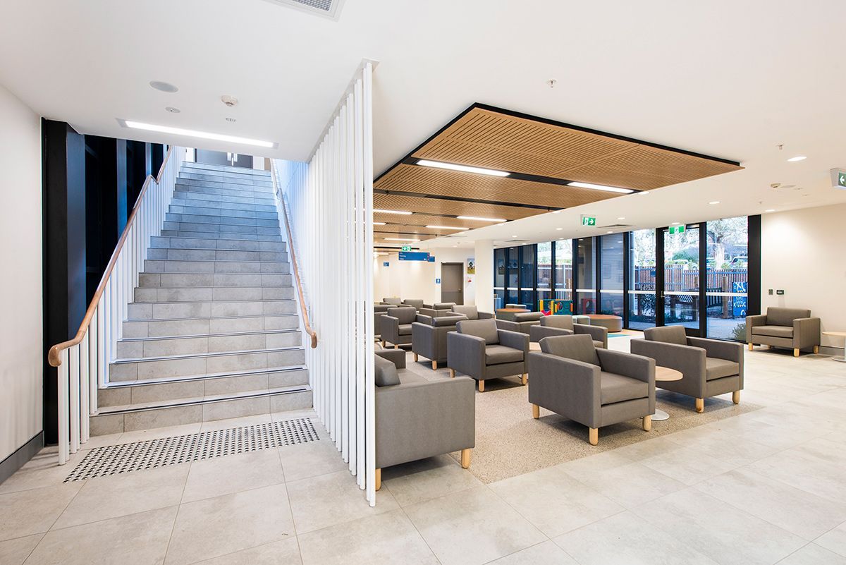 A waiting room with lots of grey couches and a staircase to the left — Commercial Painting Group in Kembla Grange, NSW