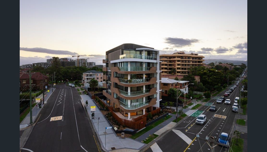 A street with a road and a car driving past an apartment building — Commercial Painting Group in Kembla Grange, NSW