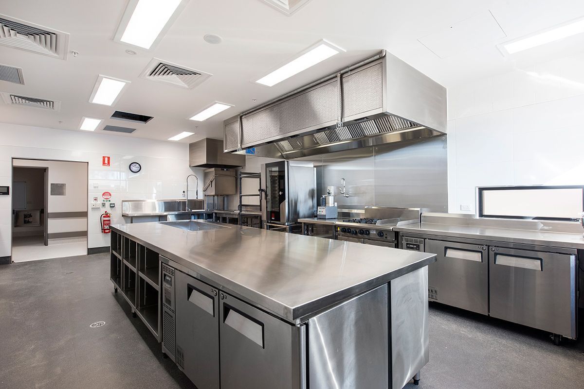 A commercial kitchen with silver benches — Commercial Painting Group in Kembla Grange, NSW