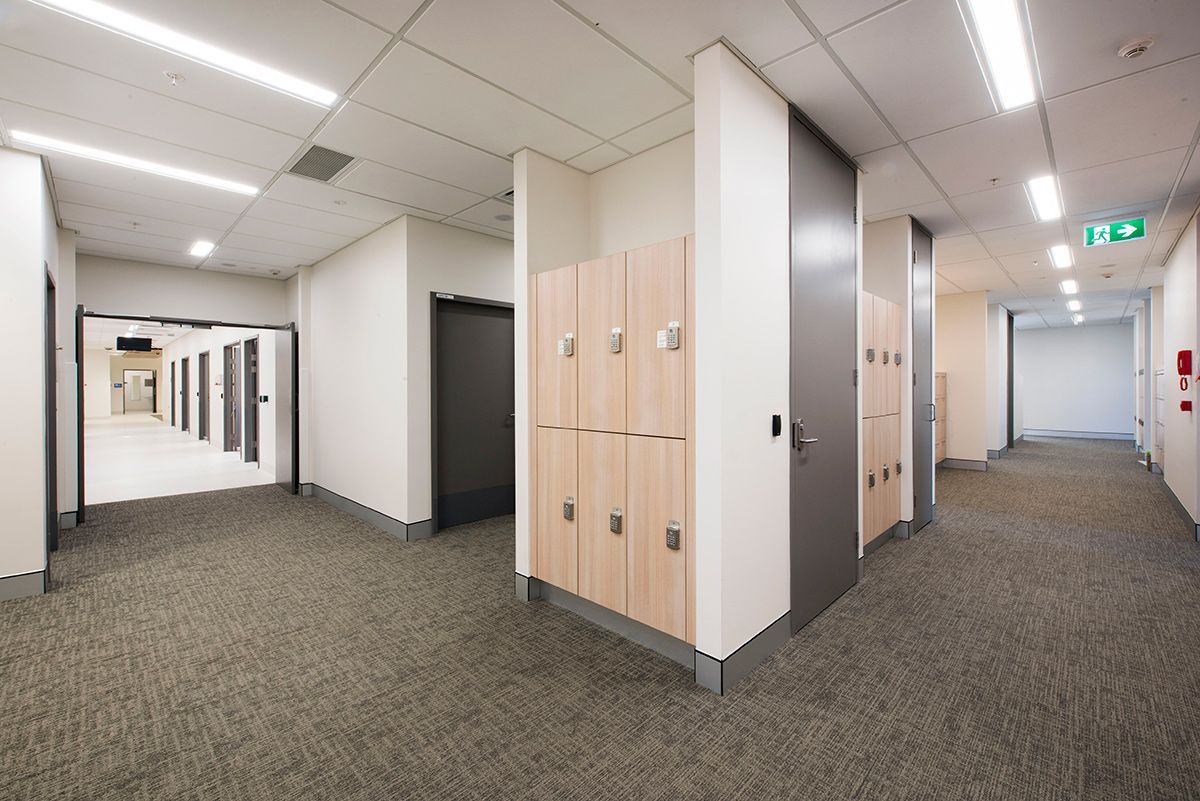A room with lots of wooden cupboards and grey doors — Commercial Painting Group in Kembla Grange, NSW
