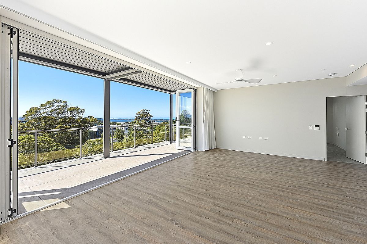 A big empty room with open doors looking out to trees and the ocean — Commercial Painting Group in Kembla Grange, NSW