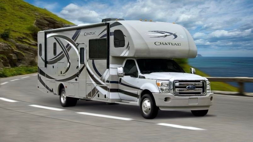 A woman is sitting next to a trailer holding a baby. 