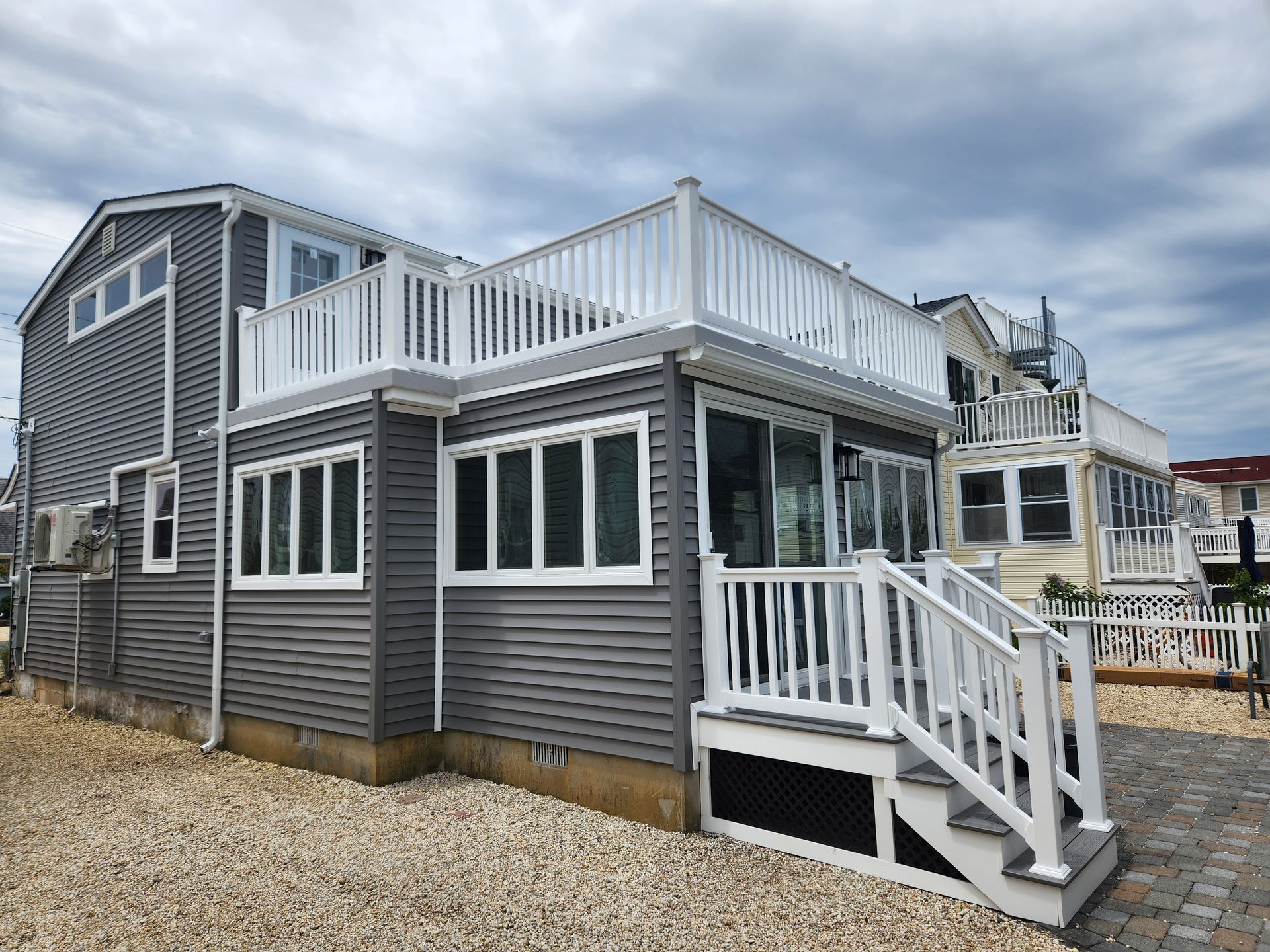 A large gray house with a white deck and stairs