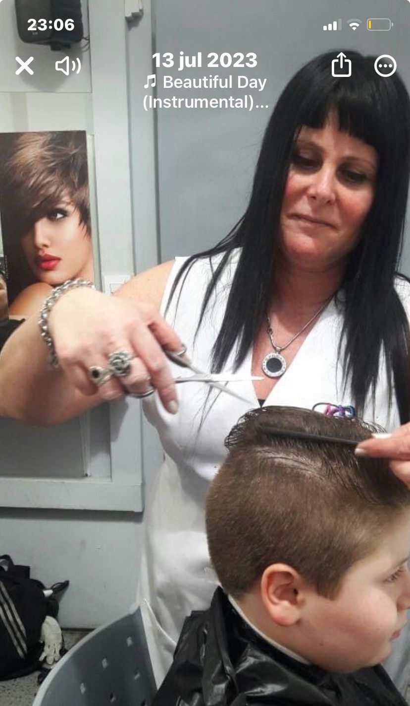 Peluquera cortando el pelo a una clienta en un salón luminoso y moderno.