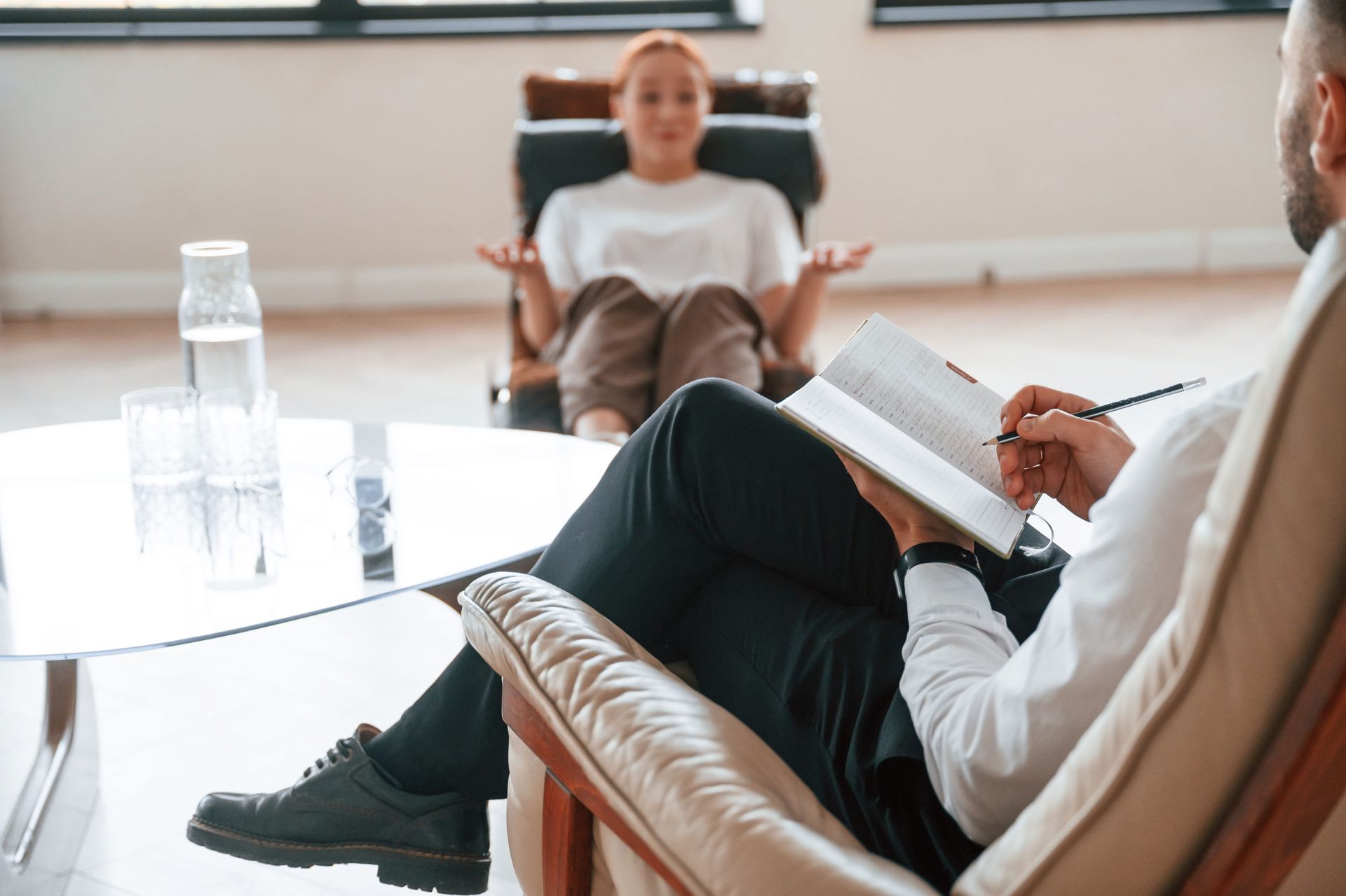 A person sitting in a therapy session looking reflective, representing betrayal trauma therapy