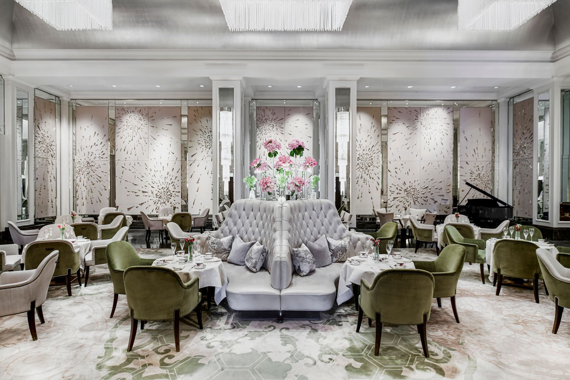 Elegant banquet hall with white and green floral decor, round tables, and plush chairs around a central centerpiece
