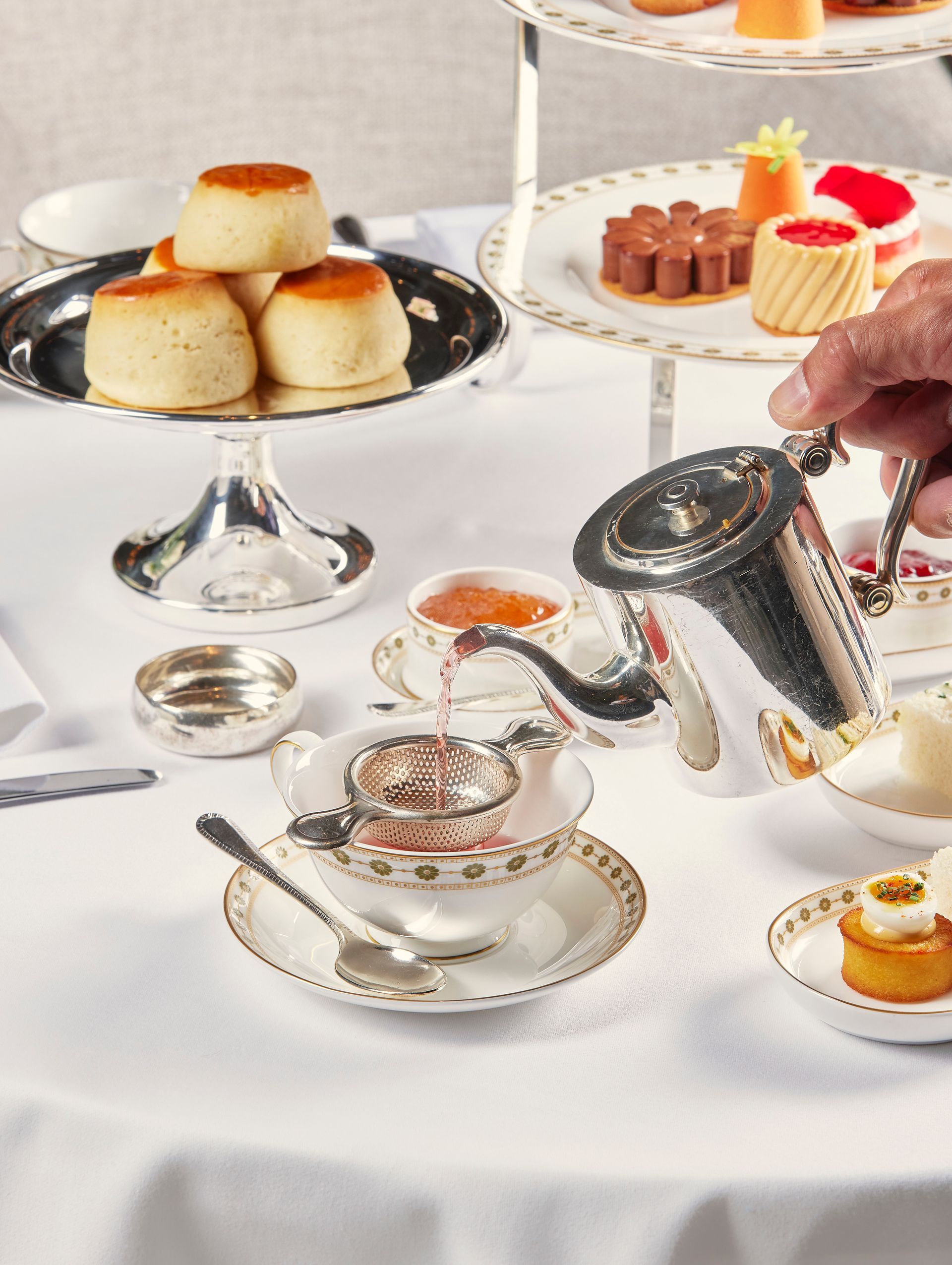 Elegant tea table with scones, pastries, and silver teapot on a white tablecloth