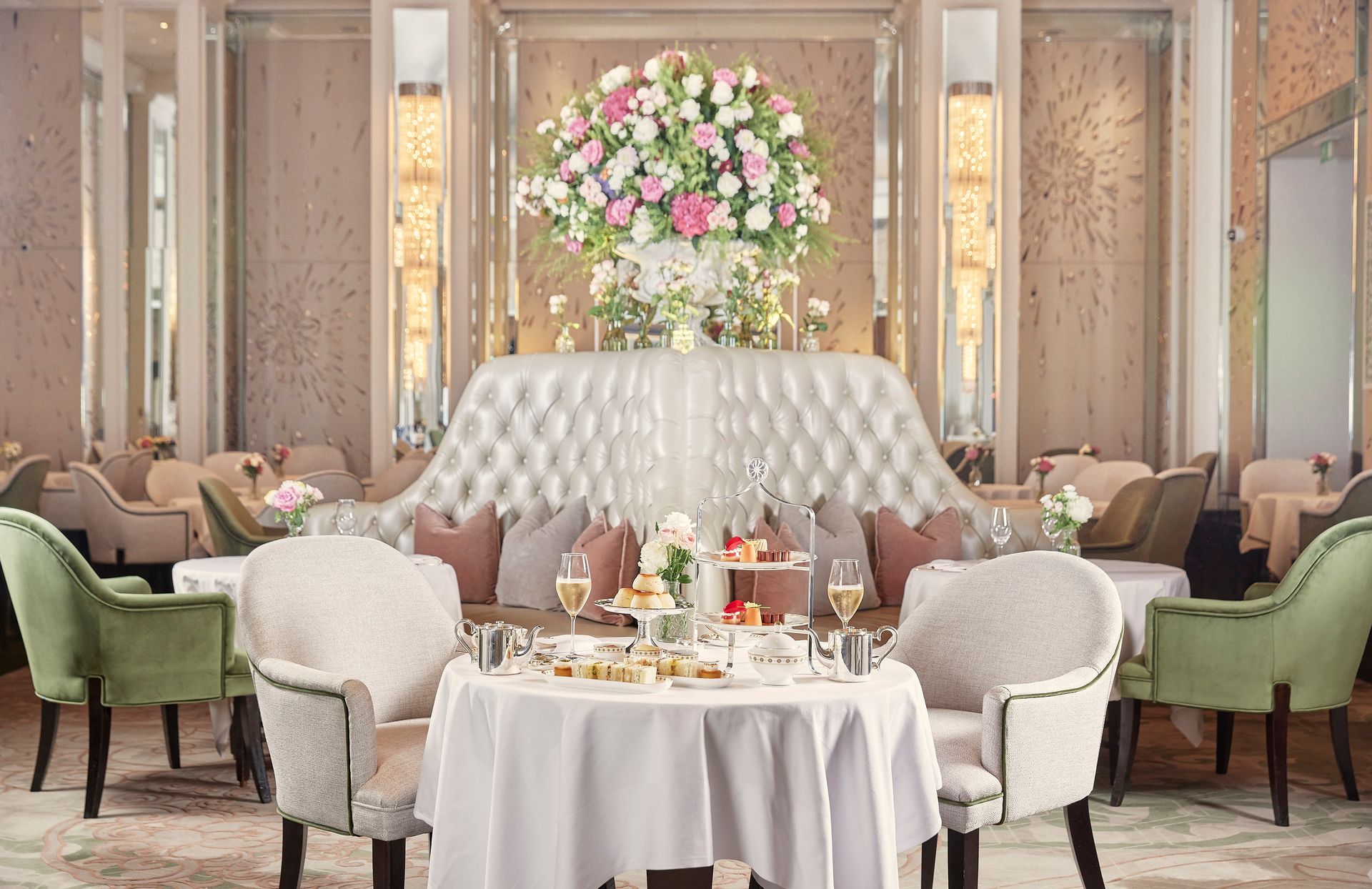 Elegant hotel lounge with pastel armchairs, round tables, and a large pink-and-white floral arrangement