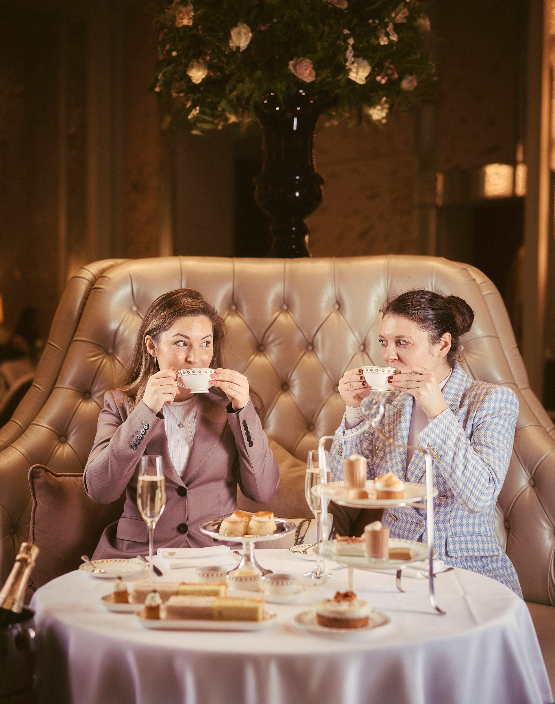 Two women sitting at a table, sharing tea and desserts in an elegant lounge