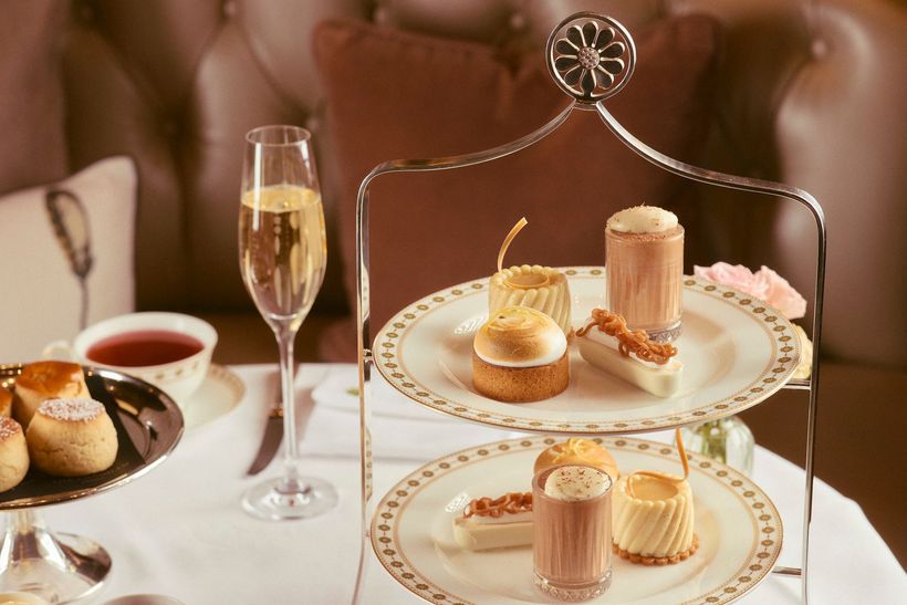 Elegant dessert table with champagne flute, tea, and assorted pastries on a two-tier tray