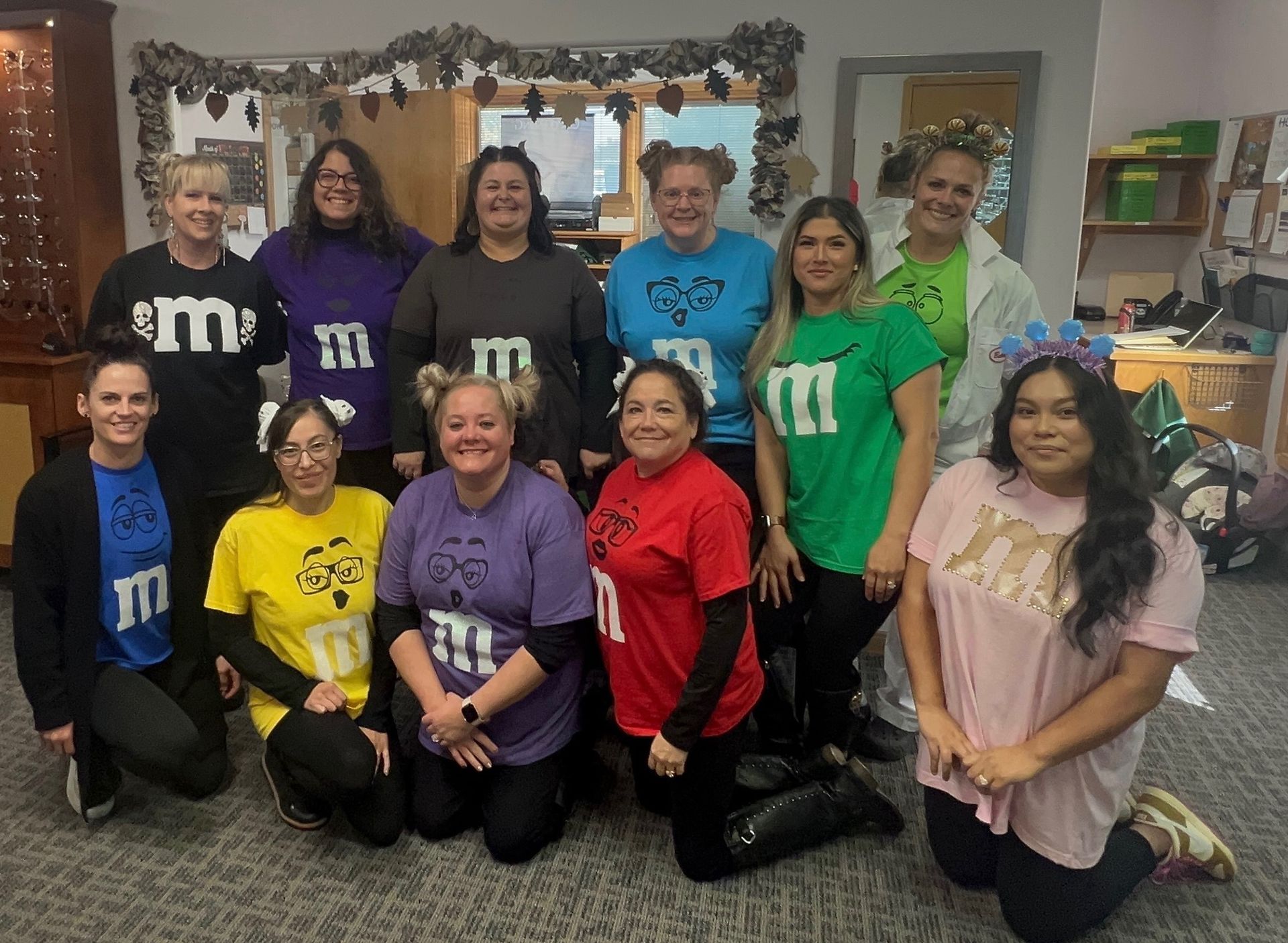 Group of people in colorful M&M costumes posing indoors.