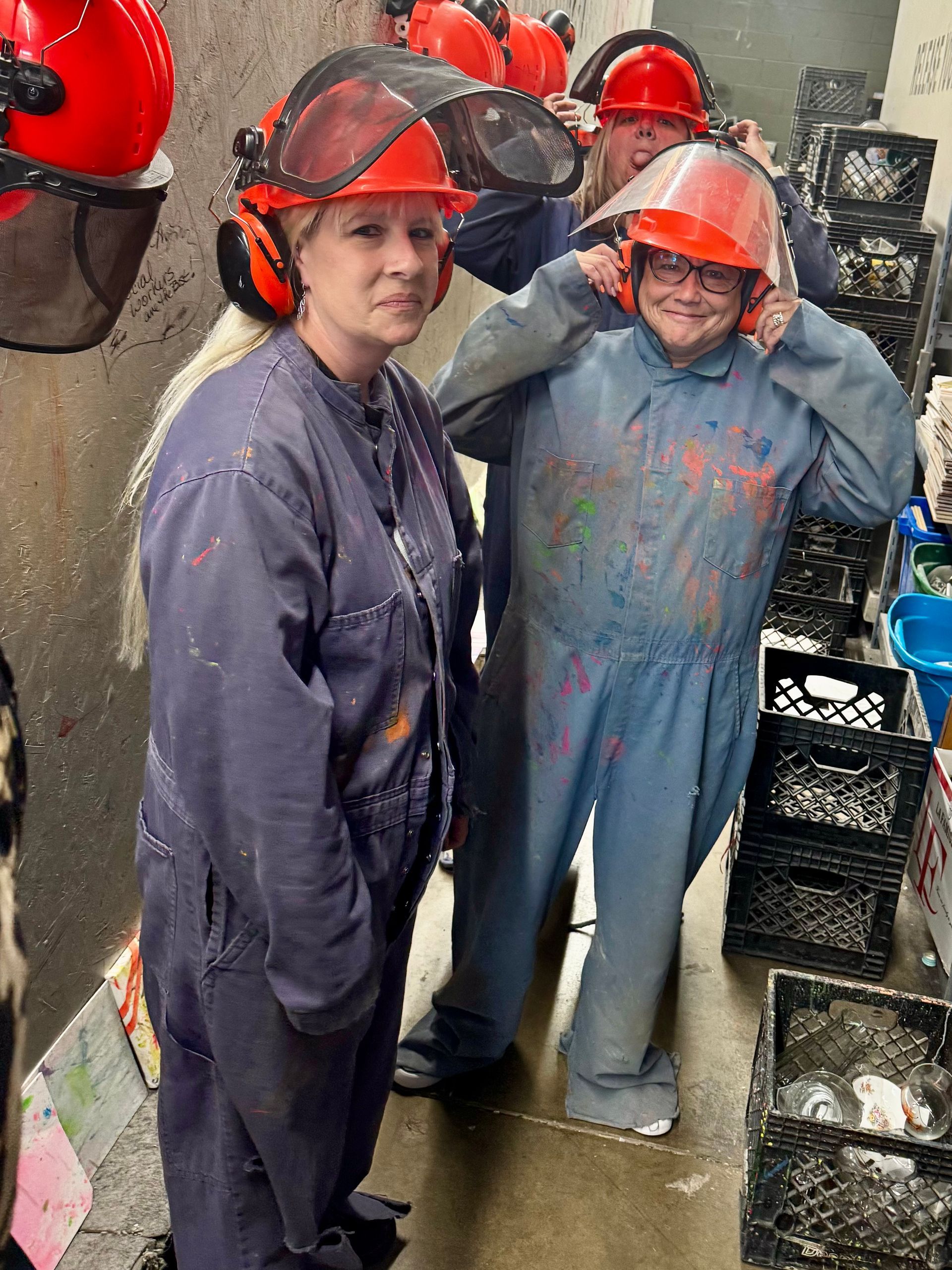 Two workers in red hard hats and protective coveralls stand in an industrial workshop.