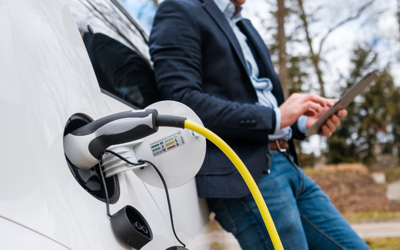 a man is using a tablet while charging his electric car .
