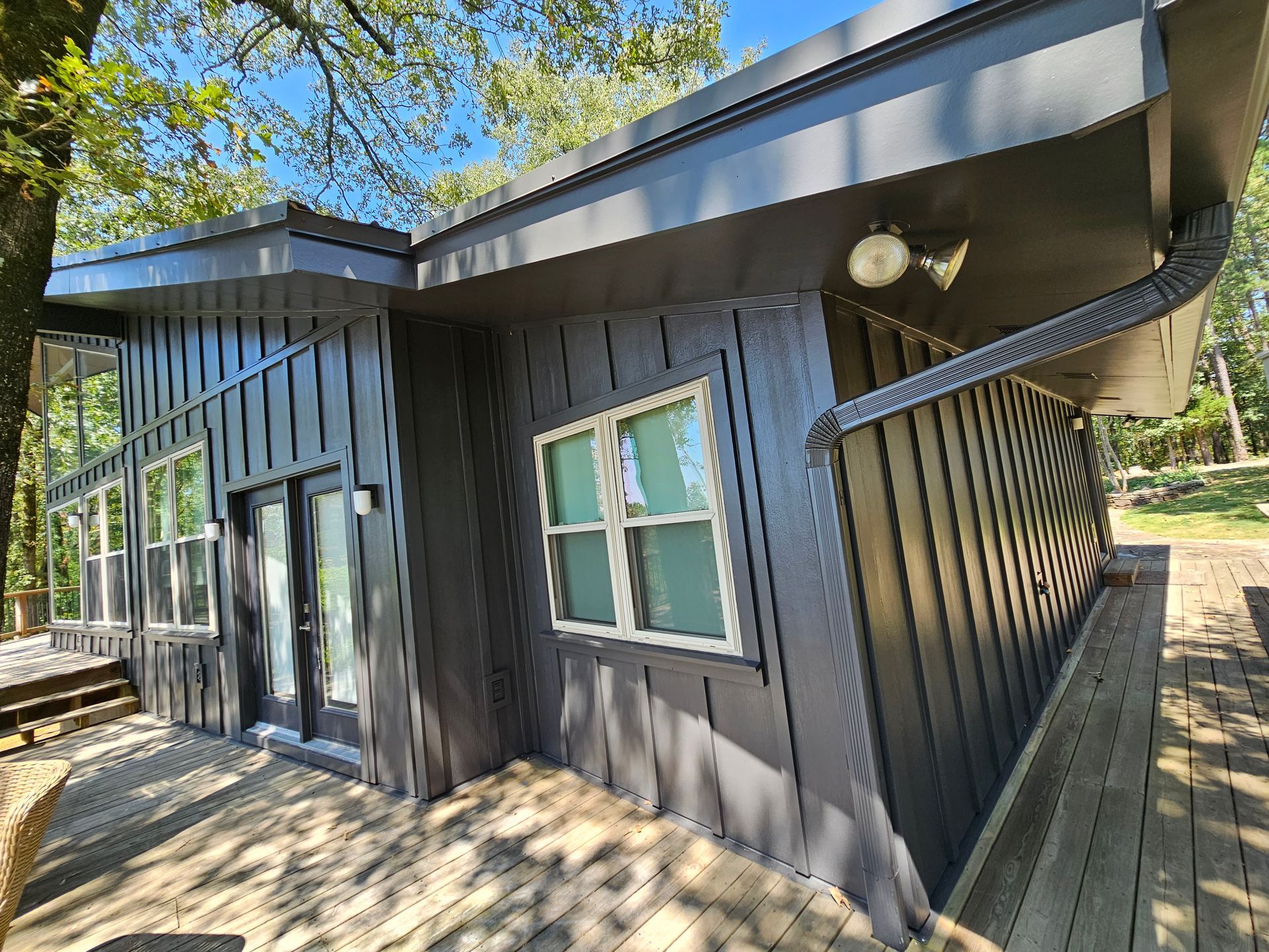 A black house with a lot of windows and a wooden deck.