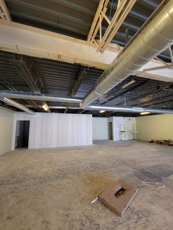 A large empty room with a lot of pipes hanging from the ceiling.