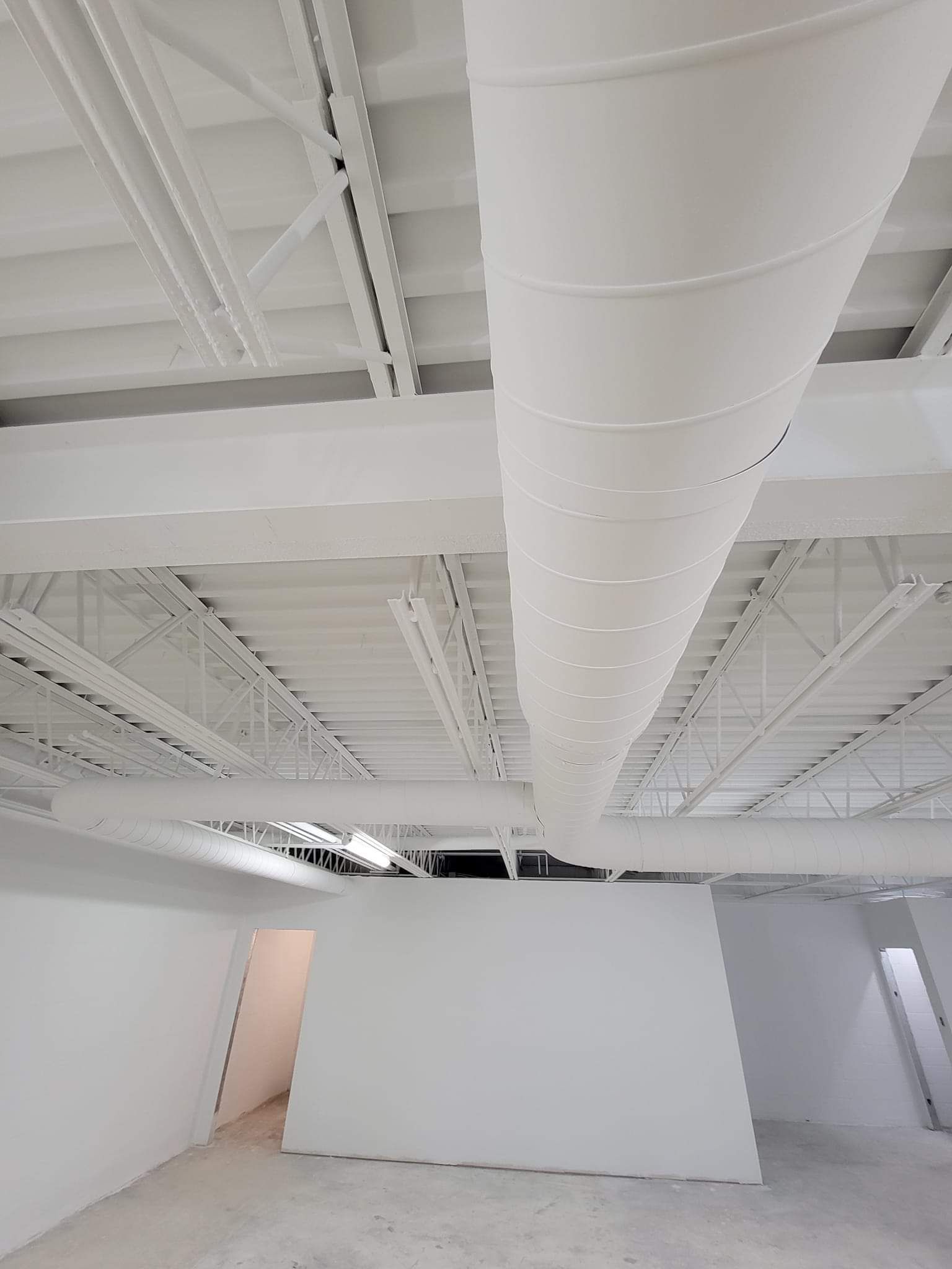 A large white pipe is hanging from the ceiling of a building.