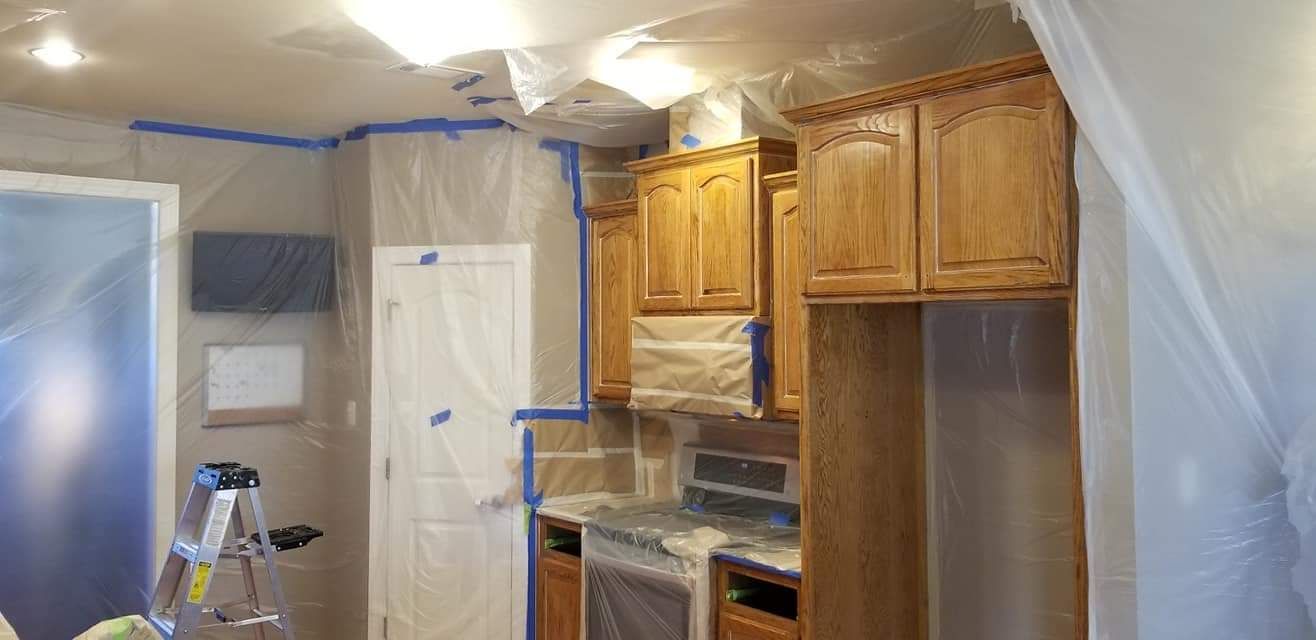 A kitchen is being painted and covered in plastic.