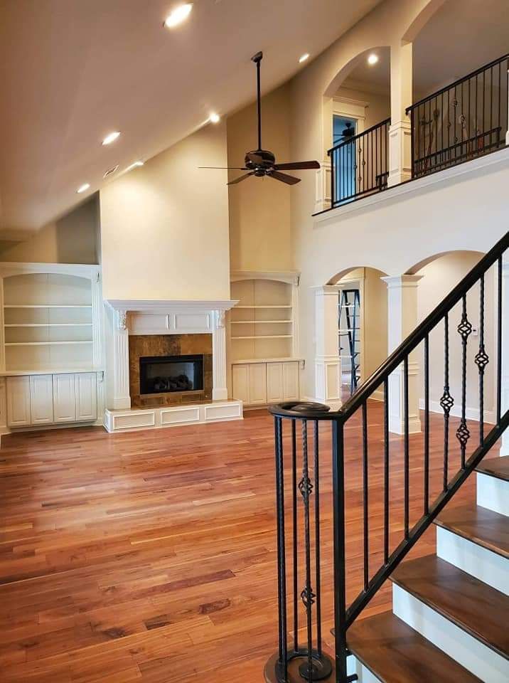 A living room with hardwood floors a fireplace and stairs