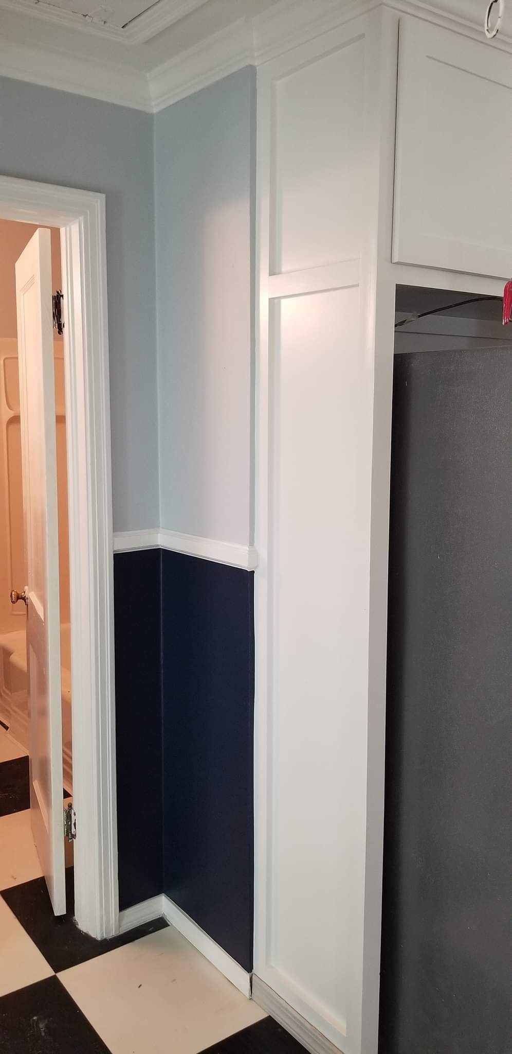 A kitchen with blue and white walls and a black refrigerator.