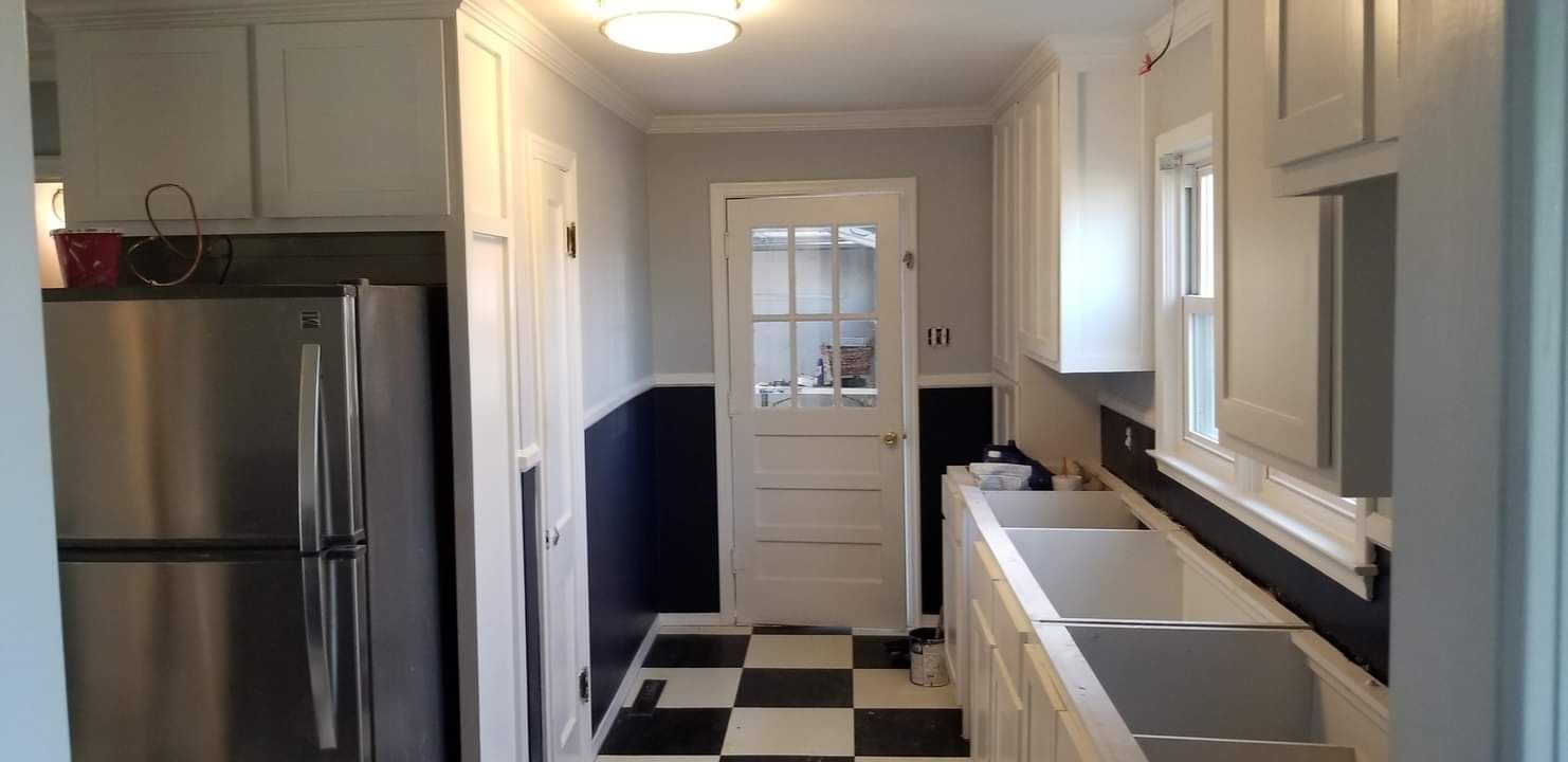 A kitchen with a stainless steel refrigerator and a black and white checkered floor