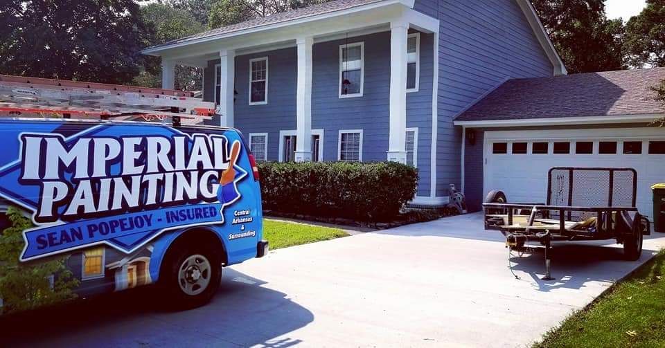 A blue imperial painting van is parked in front of a house