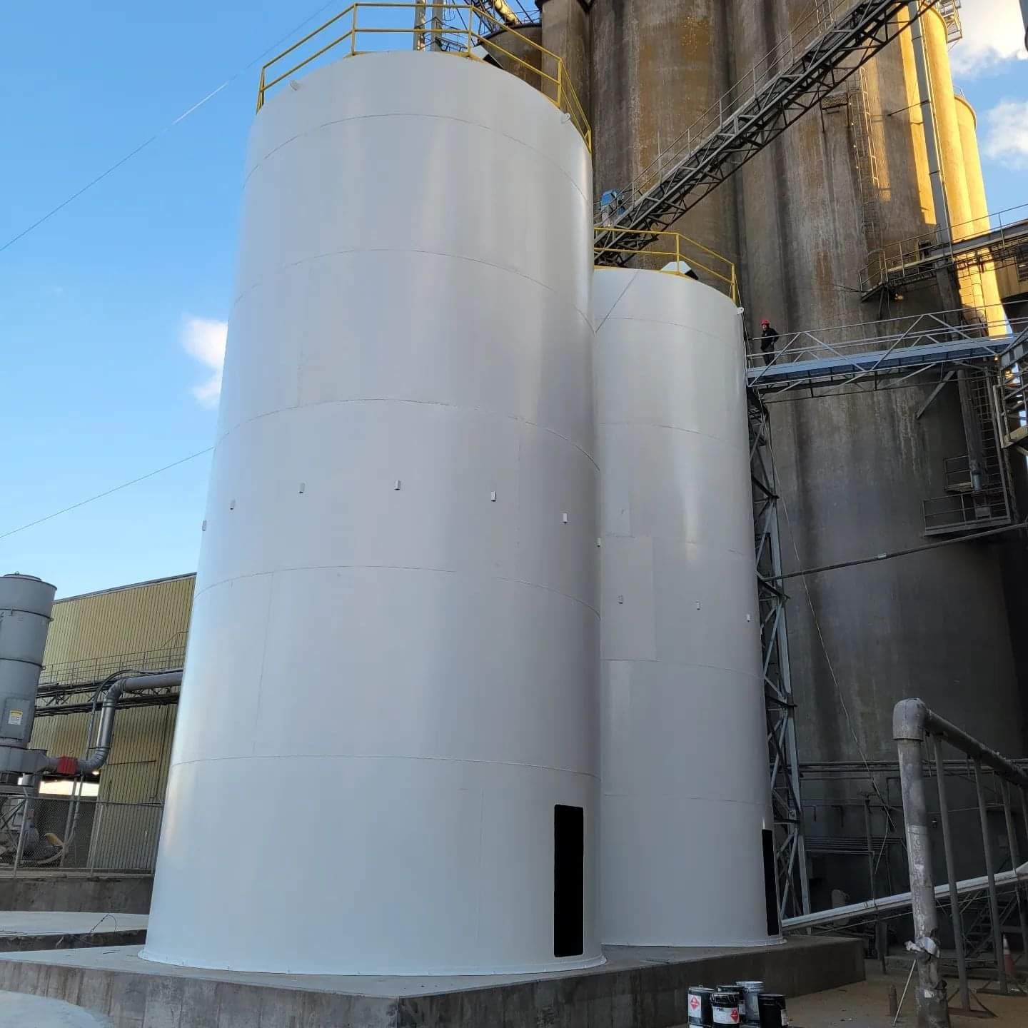 Two large white tanks are sitting next to each other in front of a building.