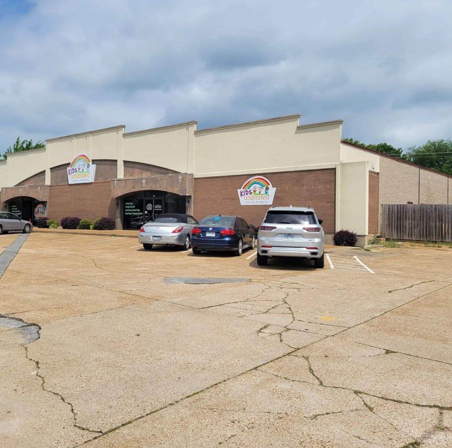 A row of cars are parked in front of a building.